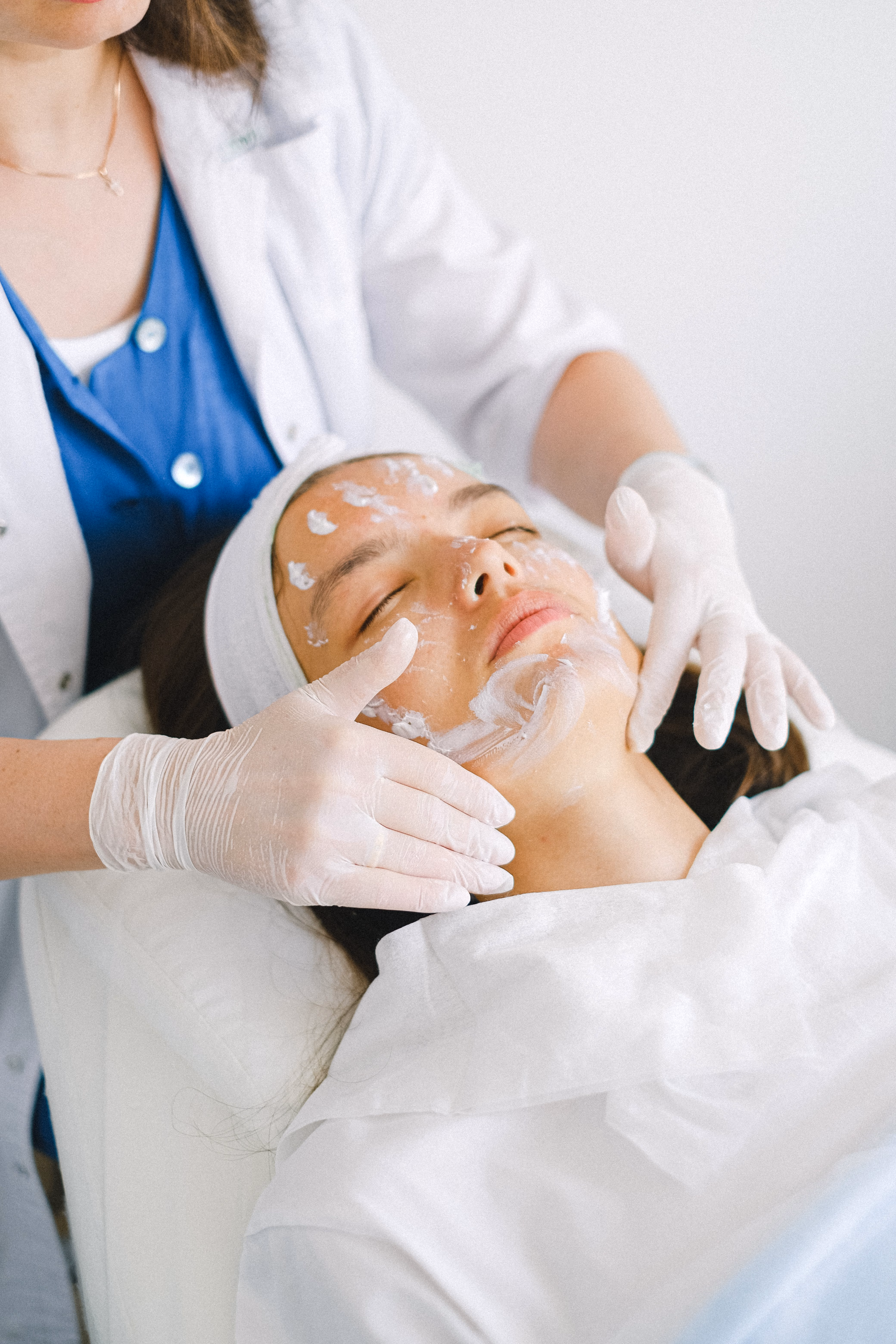 Cosmetologist applying a facial mask on a client in a spa salon